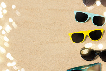 Fototapeta na wymiar summer, eyewear and accessory concept - different sunglasses on beach sand