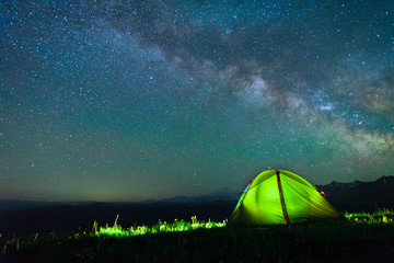tourist tent of green color against the night sky with the Milky Way