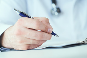 Male physician medicine doctor or pharmacist writing prescription on special form sitting at worktable. Medical care, pharmacy or health insurance concept.