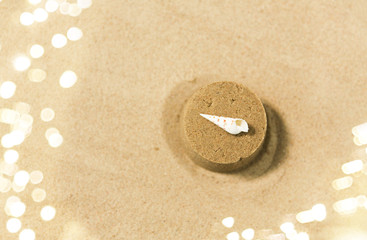 Fototapeta na wymiar toys, childhood and vacation concept - sand shape made by toy mold with shell on top on summer beach