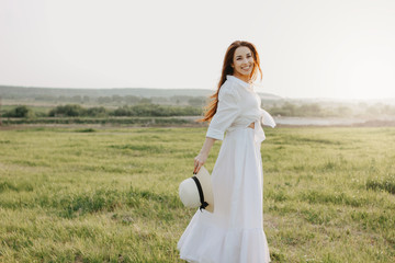 Beautiful carefree long hair asian girl in white clothes and straw hat enjoys life in nature field...