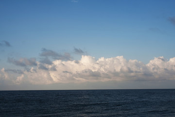 Obraz premium Dark blue sea and light blue sky with clouds