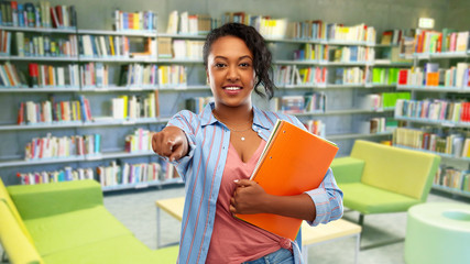 education, school and people concept - happy african american young student woman with notebooks over reading room of library background