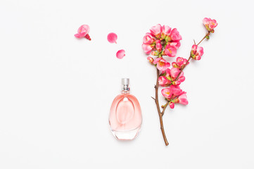 Bottle of women's perfume with pink spring flowers on light gray background top view flat lay copy...