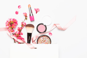 Different makeup cosmetic. Ball blush rouge lipstick concealer bottle of perfume makeup brush spring pink flowers in white gift package on light background top view flat lay. Beauty fashion background