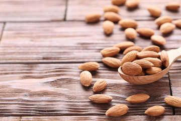 Almonds with spoon on brown wooden table