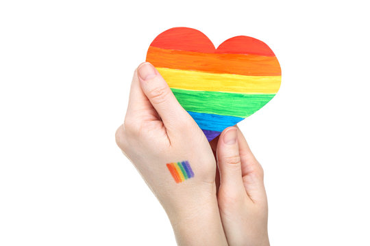 Female hands holding rainbow paper heart on white background