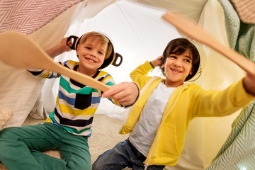 Obraz premium childhood and hygge concept - happy little boys with cooking pots playing in kids tent at home