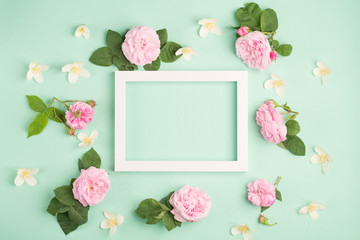 Fototapeta na wymiar Beautiful rose flowers and blank frame on pastel mint background. Soft light color. Top view, copy space.