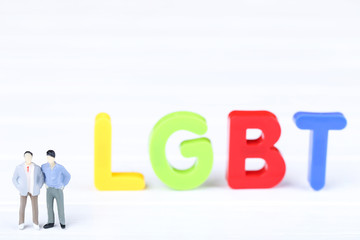 Miniature people with abbreviation LGBT on white background