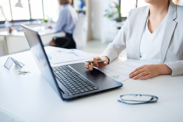 business and people concept - businesswoman with laptop computer and papers working at office