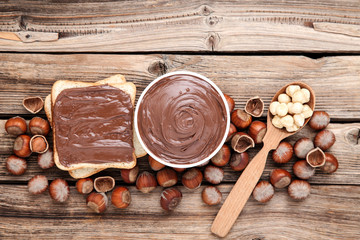 Bread with melted chocolate and hazelnuts on brown wooden table