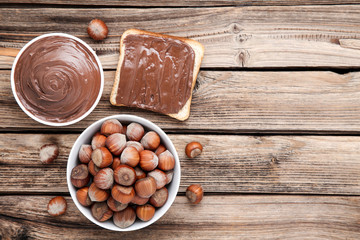 Bread with melted chocolate and hazelnuts on brown wooden table