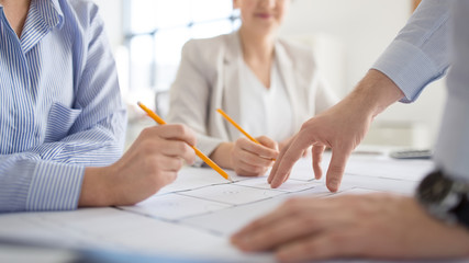 architecture, construction business and people concept - close up of architects discussing blueprint of house project at office