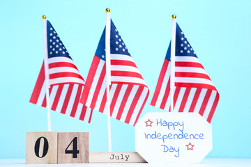 Obraz premium Text Happy Independence Day with american flags and cube calendar on blue background