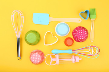 Cupcake cases with kitchen utensils on yellow background