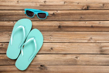 Pair of flip flops with sunglasses on brown wooden table