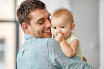 family, fatherhood and people concept - happy father holding little baby daughter at home