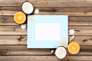 Wooden blank frame with seashells and fruits on brown table