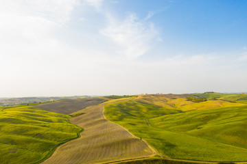 Val d'Orcia in Toscana, vista delle infinite valli verdi e d'orate di grano tra i colli senesi.
