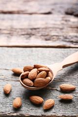 Almonds with spoon on grey wooden table