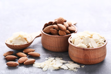 Almonds in bowls and spoon on grey wooden table