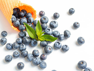 Fresh blueberries with a mint leaf in waffle cone isolated on white background. Closeup view