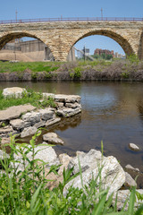 Fototapeta na wymiar Cityscape scene of downtown Minneapolis, as seen from Mill Ruins Park. View of the Stone Arch bridge on sunny spring day