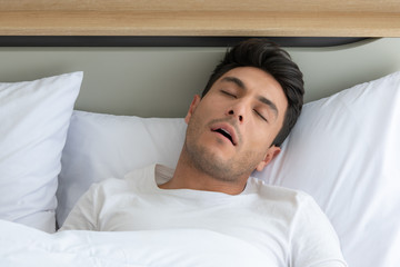 Man relaxing in the white bedroom Of the apartment With various emotions in the morning