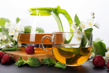 Jasmine green tea in a cup and a teapot on a dark board. White background