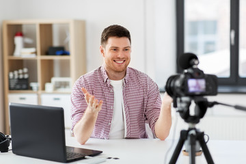 blogging, videoblog and people concept - male blogger with camera recording video blog at home...