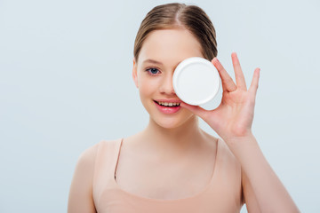 happy teenage girl with obscure face holding cosmetic cream isolated on grey
