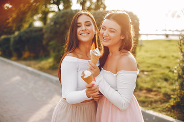 Fototapeta premium Beautiful girls in a park. Friends have fun in a summer city. Ladies with an ice cream