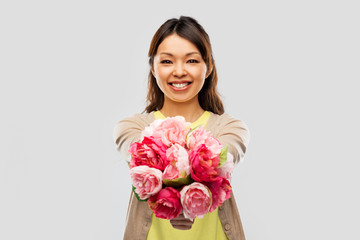 people and international women's day concept - happy asian young woman with bunch of peony flowers over grey background