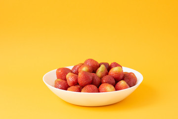 summer berry. juicy red strawberries on white plate on yellow background. Delicious breakfast snack. Vegetarian food. useful vitamins. isolated.