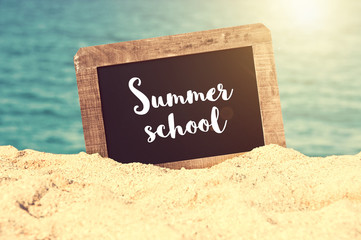 Summer school written on a vintage chalkboard in the sand of a beach, summer university concept