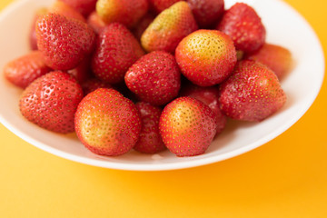 summer berry. juicy red strawberries on white plate on yellow background. Delicious breakfast snack. Vegetarian food. useful vitamins. isolated.
