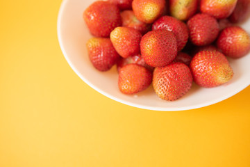 summer berry. juicy red strawberries on white plate on yellow background. Delicious breakfast snack. Vegetarian food. useful vitamins. isolated.