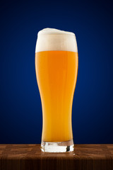 misted full cup of cold beer on a wooden table