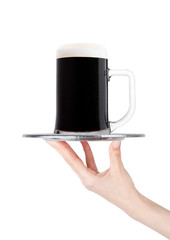 Hand holds tray with cold stout dark beer with dew