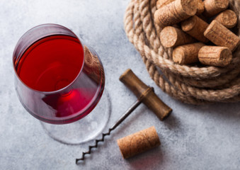 Elegant glass of red wine with corks and opener on stone kitchen table background. Top view