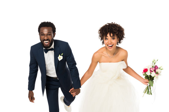 happy african american bride in wedding dress holding hands with bridegroom isolated on white
