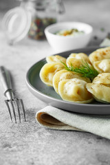 Meat dumplings - russian pelmeni, ravioli with meat on a grey plate.