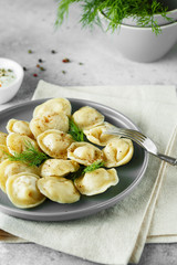 Meat dumplings - russian pelmeni, ravioli with meat on a gray plate.