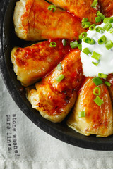 Russian stuffed cabbage rolls served with tomatoes, green onions and sour cream in heat-resistant black dishes on a gray background. Food photography.