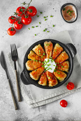 Russian stuffed cabbage rolls served with tomatoes, green onions and sour cream in heat-resistant black dishes on a gray background