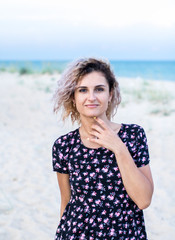 tanned beautiful young woman in cute dresswith flowers on the beach in clouds weather