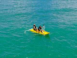 Aerial view of strong young active men kayaking on the clear blue  turquoise water of the ocean. Active vacation. Praia do Forte, Brazil