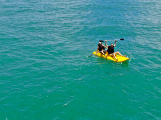Fototapeta na wymiar Aerial view of strong young active men kayaking on the clear blue turquoise water of the ocean. Active vacation. Praia do Forte, Brazil
