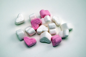 White and pink heart-shaped marshmallows lie on a white table. Pink mood.